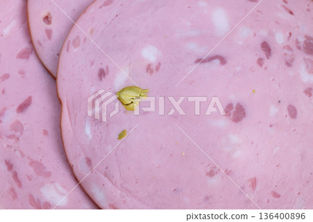 Overlapped sausage slices with pistachio bits, festive platter mood for entertaining with cheese and crackers implied, warm tones and inviting snack presentation for gatherings 136400896