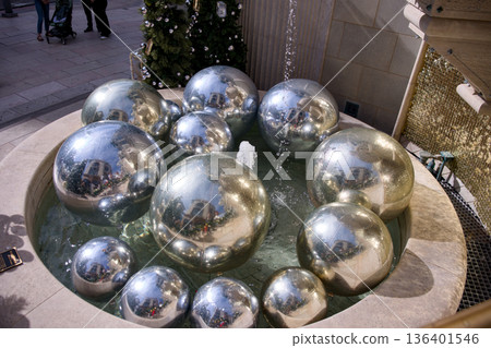 Modern fountain with reflective silver spheres and holiday decor 136401546