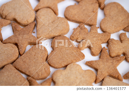 Gift ready heart and star cookies stacked on white paper, warm brown tones and homemade bakery vibe, suitable for packaging mockups and seasonal gift guide visuals 136401577