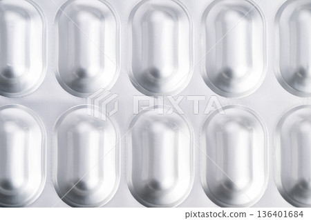 Detailed medical overview. Reflective metallic foil with pill cavities detailed. Sterile clinical appearance highlighting texture and repetitive patterns in macro shot Detailed medical overview. Reflective metallic foil with pill cavities detailed. Sterile clinical appearance highlighting texture and repetitive patterns in macro shot 136401684