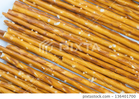 Salted pretzel sticks arranged neatly. Crunchy pretzels with coarse salt in orderly rows. Golden crisp pretzels sprinkled with salt crystals on plain background Salted pretzel sticks arranged neatly. Crunchy pretzels with coarse salt in orderly rows. Golden crisp pretzels sprinkled with salt crystals on plain background 136401700
