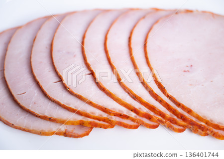Preparing ingredients for sandwich creation. Assembling ham slices for delicious sandwich. Arranging ham slices on bread with garnishes to prepare tasty sandwich dish 136401744