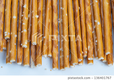 Snack moment broken pretzel ends scattered on pale surface, crumb fragments, coarse salt crystals, casual comfort food vibe, handheld snack suggestion, textured closeup 136401767