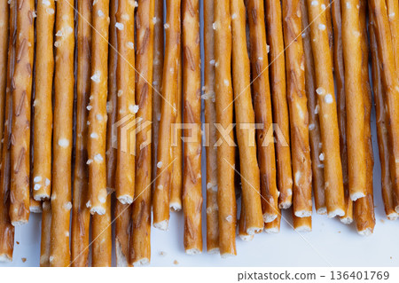 Evenly lined salted snack sticks topview showing uniform spacing, scattered salt particles, neutral backdrop, repetitive pattern, tactile crunchy appeal, simple flatlay Evenly lined salted snack sticks topview showing uniform spacing, scattered salt particles, neutral backdrop, repetitive pattern, tactile crunchy appeal, simple flatlay 136401769
