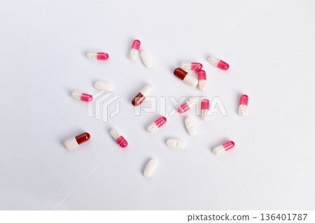 Pills highlight message. Red and white pills spread out. Empty space accentuates pill quantity visually. Clinical style emphasizes significant number of pills shown Pills highlight message. Red and white pills spread out. Empty space accentuates pill quantity visually. Clinical style emphasizes significant number of pills shown 136401787
