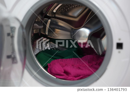 Colorful clothes spinning inside modern front loading washing machine drum Colorful clothes spinning inside modern front loading washing machine drum 136401793
