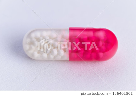 Pink capsule details. Translucent pink capsule under light. Laboratory illuminated pink capsule with granules. Laboratory testing shows pink capsule with granules and translucency 136401801