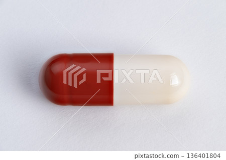 Closeup single red and white capsule highlighting glossy surface and seam, macro product shot for branding and packaging, isolated on neutral background with soft shadow 136401804