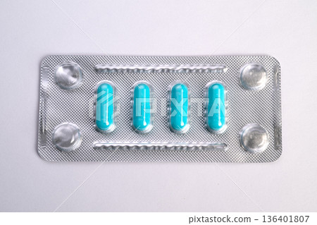 Turquoise capsules in small blister arranged in row, laboratory sample vibe, sterile foil reflection, clinical inspection and quality control context, macro topdown perspective 136401807