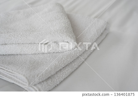 Clean folded white towels on hotel bed in bright room 136401875