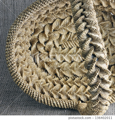 Woven straw basket against burlap background. Close-up. Details. Eco-friendly. Handmade basket for interior decoration and use as container for collecting fruits, vegetables, and mushrooms. Woven straw basket against burlap background. Close-up. Details. Eco-friendly. Handmade basket for interior decoration and use as container for collecting fruits, vegetables, and mushrooms. 136402011