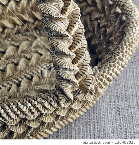 A woven straw basket against a burlap background. Close-up. Details. Eco-friendly. Handmade basket for interior decoration and use as a container for collecting fruits, vegetables, and mushrooms. A woven straw basket against a burlap background. Close-up. Details. Eco-friendly. Handmade basket for interior decoration and use as a container for collecting fruits, vegetables, and mushrooms. 136402025