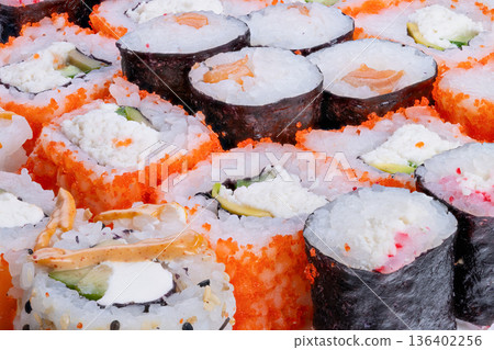 Colorful sushi with crunchy cucumber. Closeup of vibrant sushi with crispy cucumber and tobiko. Detailed view of sushi rolls featuring orange tobiko and fresh vegetables Colorful sushi with crunchy cucumber. Closeup of vibrant sushi with crispy cucumber and tobiko. Detailed view of sushi rolls featuring orange tobiko and fresh vegetables 136402256
