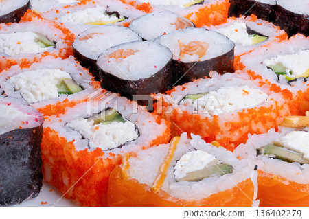 Closeup sushi rolls in vibrant overhead layout, repeating patterns and diverse textures with orange roe highlights, editorial flatlay for social media and celebratory snack scenes 136402279