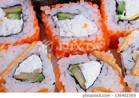 Colorful avocado sushi rolls with citrus hints. Radiant avocado sushi preparation garnished with cucumber strips and citrus flavoring for healthconscious diners 136402369