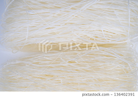 Pale rice vermicelli close up texture, fine translucent strands stacked in warm light, handcrafted pantry mood, ideal for recipe visuals and culinary branding, soft tactile feel Pale rice vermicelli close up texture, fine translucent strands stacked in warm light, handcrafted pantry mood, ideal for recipe visuals and culinary branding, soft tactile feel 136402391