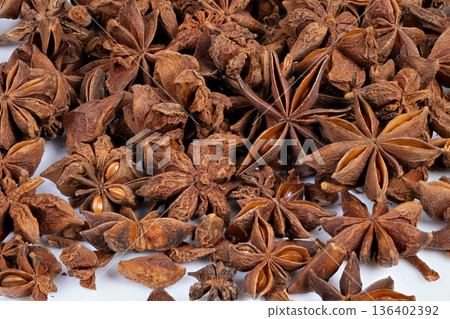 Spicy seed cluster. Detailed view of dense dried anise pods and seeds. Textured image showcasing clustered dried star anise with earthy tones for herbal packaging 136402392