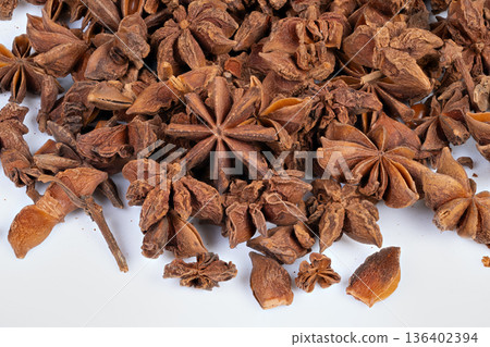 Brown starshaped spice macro shot. Close range image of star anise pods on white background. Detailed macro photograph of dried star anise spice on plain white backdrop 136402394