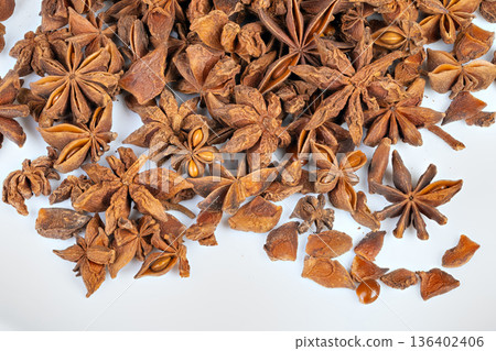 Marketstyle pile of star anise pods on crisp white backdrop, rich brown tones evoke spice stall and culinary trade, suitable for ecommerce, food blogs, and wholesale listings 136402406