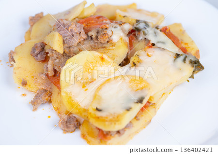 Savory baked potato with sausage. Golden potato casserole topped with herbs and cheese. Delicious cheesy potato bake with sausage and crispy edges for food photography 136402421