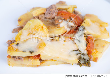Refined layered potato dish decorated with herbs and creamy cheese topping. Sophisticated multilayered potato presentation featuring herbs and cheese in elegant style Refined layered potato dish decorated with herbs and creamy cheese topping. Sophisticated multilayered potato presentation featuring herbs and cheese in elegant style 136402425