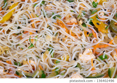 Tasty noodle dish. Vibrant stirfried rice and vegetable medley with glossy sauce. Colorful and enticing rice noodle stirfry featuring crunchy cashews and fresh vegetables Tasty noodle dish. Vibrant stirfried rice and vegetable medley with glossy sauce. Colorful and enticing rice noodle stirfry featuring crunchy cashews and fresh vegetables 136402496