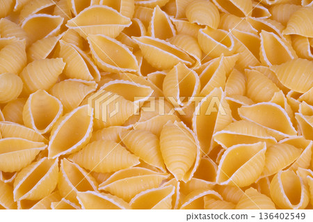 Scattered pasta shells ready recipe prep, tactile semolina dust, rustic cooking vibe, ingredient photography for cookbooks, flatlay potential for content creators 136402549