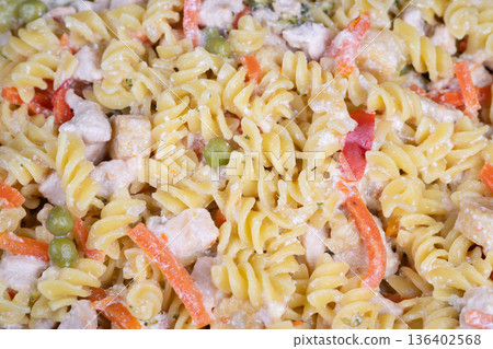Creamy fusilli salad on display, stacked in clear containers at deli counter, garnished with parsley and light mayonnaise dressing, ready for takeaway during busy lunchtime 136402568