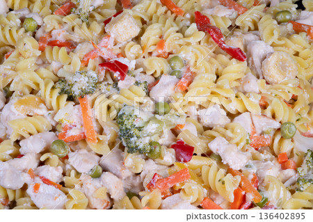 Hearty pasta with vegetables and cheese. Closeup of creamy fusilli with colorful veggies. Homestyle creamy fusilli with vibrant vegetables and subtle sauce for cozy meals 136402895
