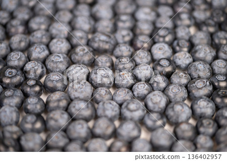 Closeup cluster ripe blueberries showcasing delicate bloom and matte skin, shallow depth of field, cool bluegray palette evokes calm freshness for product and editorial use 136402957