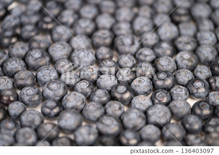 Tight macro blueberries showing texture, powdery coating and circular crown details, cool desaturated palette, editorial food photography, backdrop for healthy lifestyle branding 136403097