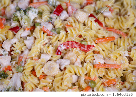 Vegan fusilli with peas, peppers and carrots, plantforward bowl emphasizing clean eating and bright color, broccoli florets and corn kernels add texture, light olive oil sheen 136403156