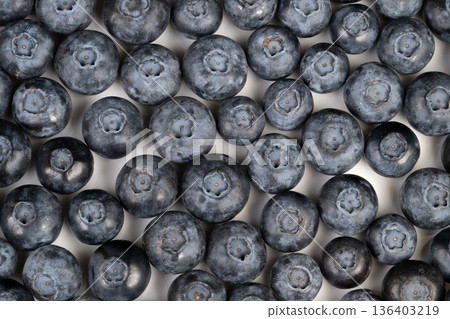 Closeup symmetrical arrangement of blueberries highlighting circular forms and surface detail, studio lighting emphasizes contrast and clarity for artistic food studies 136403219