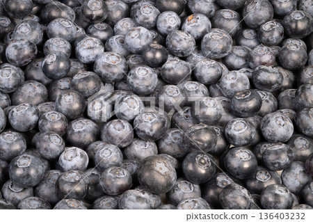 Bright blueberries scattered in container with natural skin textures. Closeup of tiny blue berries spilling from bowl showing rich hues and powdery surface textures Bright blueberries scattered in container with natural skin textures. Closeup of tiny blue berries spilling from bowl showing rich hues and powdery surface textures 136403232