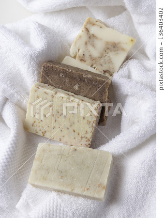 Unbranded beige and brown solid soap bars on white terry towel, bathroom spa amenities 136403402