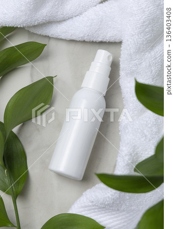 Mockup of blank white spray bottle near white bath terry towel and green leaves. Unbranded cosmetic 136403408