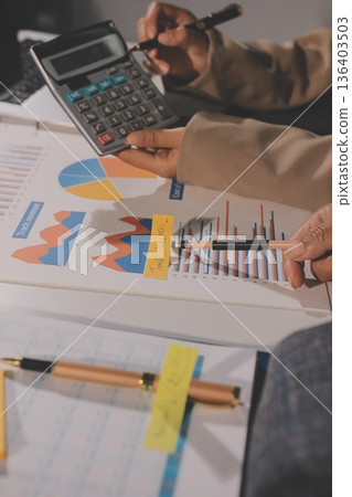 business documents on office table with tablet, smart phone and laptop and two colleagues discussing data business documents on office table with tablet, smart phone and laptop and two colleagues discussing data 136403503