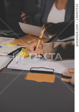 business documents on office table with tablet, smart phone and laptop and two colleagues discussing data business documents on office table with tablet, smart phone and laptop and two colleagues discussing data 136403532