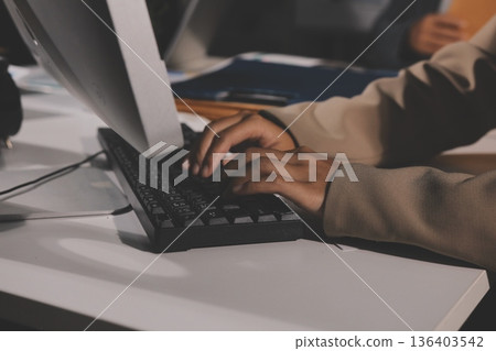 business documents on office table with tablet, smart phone and laptop and two colleagues discussing data business documents on office table with tablet, smart phone and laptop and two colleagues discussing data 136403542
