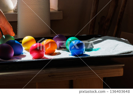 Side view of colorful dyed easter eggs in bright colors drying on a tray lined with paper towel Side view of colorful dyed easter eggs in bright colors drying on a tray lined with paper towel 136403648