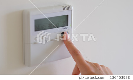 Adjusting the thermostat to create a cozy atmosphere in a modern home suitable for any season 136403928