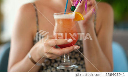 Sip of summer delight at a tropical paradise with vibrant cocktail in hand 136403941