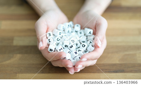 Holding letter cubes in delicate hands to spark creativity and playful word formation in a warm environment 136403966