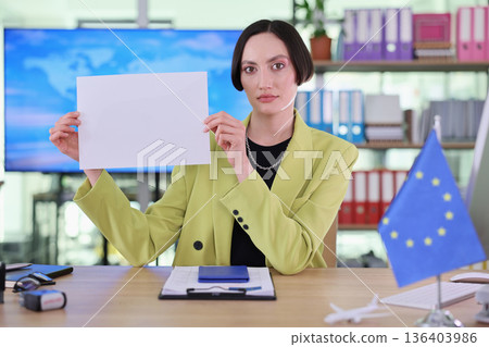 Confident business professional displays blank document in a modern office setting during a productive workday 136403986