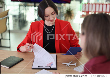 Business meeting at a modern office with two women discussing important documents and travel plans Business meeting at a modern office with two women discussing important documents and travel plans 136404022