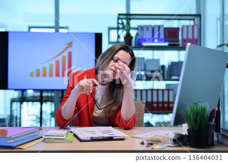 Stressful day in the office with a businesswoman managing overwhelming tasks and data analysis Stressful day in the office with a businesswoman managing overwhelming tasks and data analysis 136404031