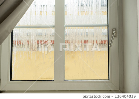 Plastic window with heavy condensation and water droplets. Indoor humidity problem Plastic window with heavy condensation and water droplets. Indoor humidity problem 136404039