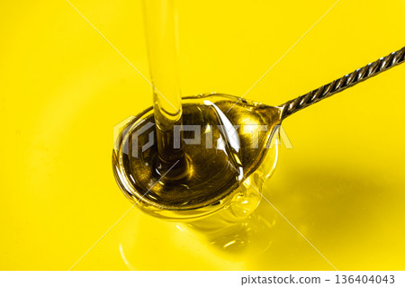 Pouring extra virgin olive oil into silver spoon Pouring extra virgin olive oil into silver spoon 136404043