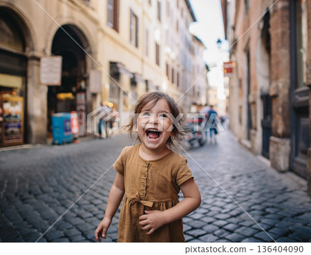 Child laughs joyfully while playing in a narrow street filled with stone pavement in a bustling city during the day 136404090