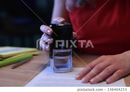 Hand seals important documents in a cozy workspace filled with soft light and focused energy during evening hours 136404253